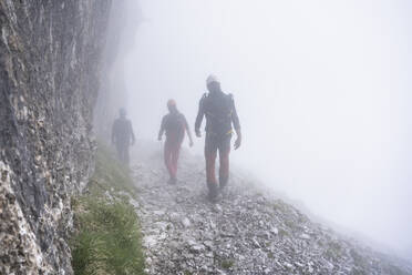 Mature men walking on mountain during foggy weather, Bergamasque Alps, Italy - MCVF00544