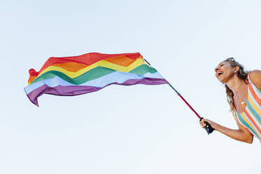 Reife Frau schwankt Homosexuell Stolz Flagge gegen klaren Himmel - CJMF00307