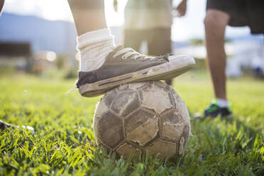 Ein Fußballspieler legt einen alten Schuh auf einen zerrissenen Fußball. - CAVF87214