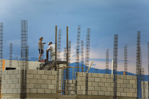 Zwei Bauarbeiter arbeiten auf dem Dach und schweißen ein Metallgeländer. - CAVF87215