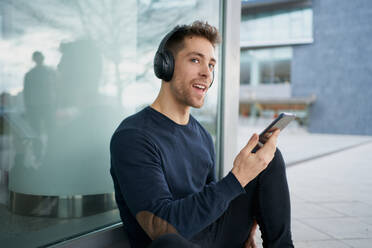 Young man with headphones on city street - CAVF87224