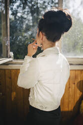 Rauchende Frau auf dem Balkon stehend mit dem Rücken - CAVF87232