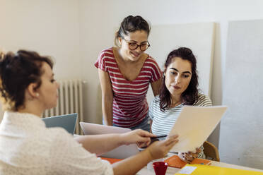 Junge Frauen mit Papieren Coworking zur Unternehmensgründung - CAVF87284