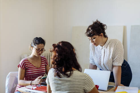 Eine Gruppe junger Geschäftsfrauen diskutiert am Tisch über einen Plan - CAVF87287