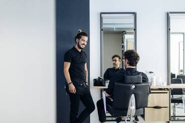 Modern barber chatting with partner in salon - CAVF87294