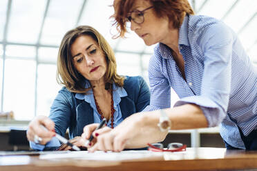 Inspirierte reife Geschäftsfrauen arbeiten gemeinsam an einem Kunstprojekt - CAVF87302