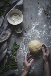 Crop shot from above of senior person kneading ball of soft dough on marble counter sprinkled with flour - ADSF01639