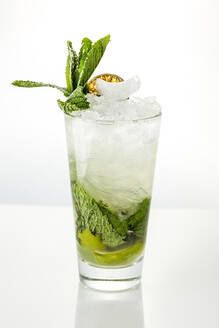 High glass with traditional Mojito cocktail garnished with dried lime and mint on black background - ADSF01657