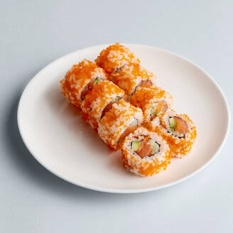 Helle köstliche japanische Sushi-Rollen mit Lachs in fliegenden Fischkaviar schön auf weißem Teller auf weißem Hintergrund von oben gesetzt - ADSF01679