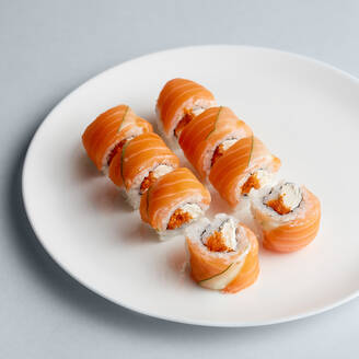 Bright delicious Japanese sushi rolls with salmon in flying fish caviar set beautifully on white plate on white background from above - ADSF01682