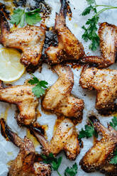 From above shot of baking tray with parchment and baked chicken wings in sesame and parsley with lemon - ADSF01683