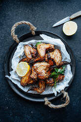 From above shot of baking tray with parchment and baked chicken wings in sesame and parsley with lemon - ADSF01685