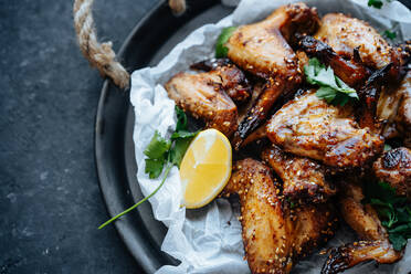 From above shot of baking tray with parchment and baked chicken wings in sesame and parsley with lemon - ADSF01687