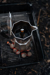 Coffee in stovetop coffee maker on top of warm charcoal in griddle - ADSF01694