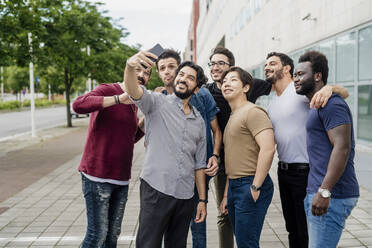 Mann macht Selfie mit männlichen Freunden auf dem Fußweg in der Stadt - MEUF01507