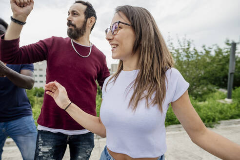 Glückliche Freunde schauen weg, während sie im Park gegen den Himmel tanzen - MEUF01529