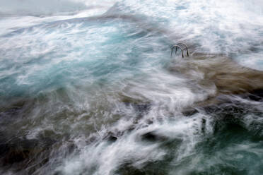 From above rock coast with ladder between water surface with foam in Hierro Island, Canary Island, Spain - ADSF01709