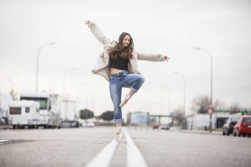 Woman dancer on ballet tips, jeans and white coat on the street and movement - ADSF01779