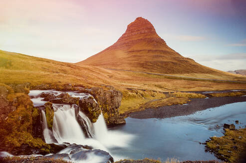 Landschaft mit schönen Wasserfällen in Langzeitbelichtung am Ufer eines Flusses mit grünen Bergspitzen im Hintergrund, Island - ADSF01783