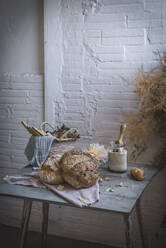 Ein Bündel trockener Nadelbaumzweige hängt über dem Tisch mit der Bäckerei in der Nähe der Stühle im Zimmer - ADSF01818