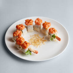 Helle köstliche japanische Sushi-Rollen mit Lachs in fliegenden Fischkaviar schön auf weißem Teller auf weißem Hintergrund von oben gesetzt - ADSF01836