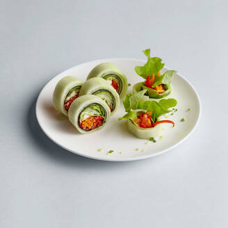 Helle köstliche japanische Sushi-Rollen mit Lachs in fliegenden Fischkaviar schön auf weißem Teller auf weißem Hintergrund von oben gesetzt - ADSF01838