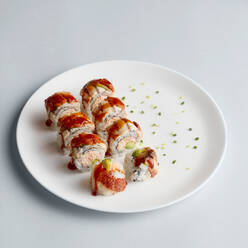 Helle köstliche japanische Sushi-Rollen mit Lachs in fliegenden Fischkaviar schön auf weißem Teller auf weißem Hintergrund von oben gesetzt - ADSF01840