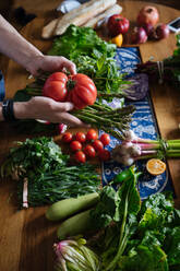 Crop view of female hands taking potherbs from elegant table with fresh healthy vegetable and fruit cooking ingredients from above - ADSF01890