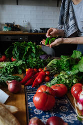 Crop Ansicht der weiblichen Hände nehmen potherbs von eleganten Tisch mit frischem gesundem Gemüse und Obst Kochen Zutaten von oben - ADSF01900