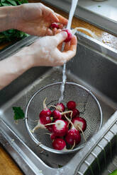 Frau wäscht frisches Gemüse in der Küche - ADSF01919