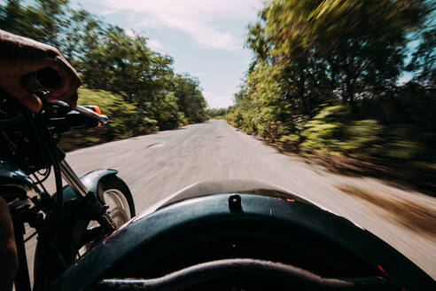 Blick aus dem Beiwagen eines Motorrads während einer schnellen Fahrt auf einer grünen, abgelegenen Straße, Kuba. - ADSF01991
