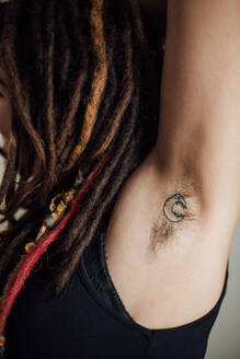 Frau mit Dreadlocks zeigt ihre behaarte Achsel mit Tattoo - ADSF02012