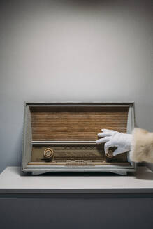 Hand des Weihnachtsmanns in Handschuh und Mantel auf einem alten Radioempfänger - ADSF02060