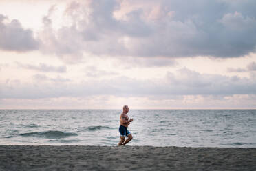 Strong old man makes exercise on the beach. - ADSF02078