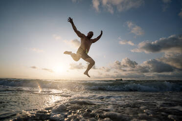 Silhouette of man jumping on beach. - ADSF02082