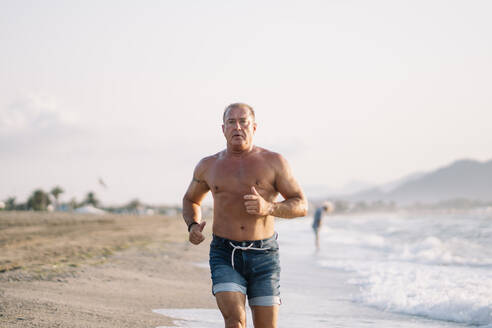 Ein kräftiger alter Mann macht Übungen am Strand. - ADSF02084