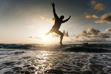 Silhouette of man jumping on beach. - ADSF02095