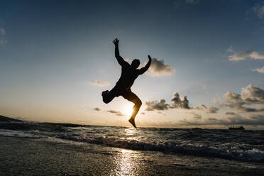 Silhouette of man jumping on beach. - ADSF02096