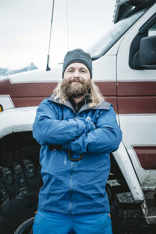 Selbstbewusster erwachsener bärtiger Mann in Freizeitkleidung, der sich mit verschränkten Armen an ein Geländewagen lehnt und in die Kamera schaut, Island - ADSF02109