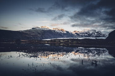 Landschaft mit abgelegenen kalten Bergen, die sich in ruhigem Wasser spiegeln, mit Schnee auf dem Boden, Island - ADSF02114