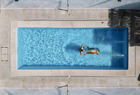 Schwuler Mann mit Gay Pride Flagge im Schwimmbad., lizenzfreies Stockfoto