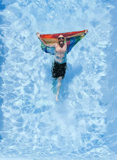 Schwuler Mann mit Gay Pride Flagge im Schwimmbad. - ADSF02122