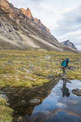 Reflection of hiker looking up at alpenglow on mountain view. - CAVF87346