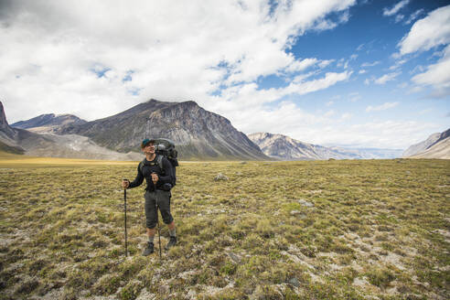 Rucksacktourist beim Wandern durch ein offenes Tal in der Arktis. - CAVF87352