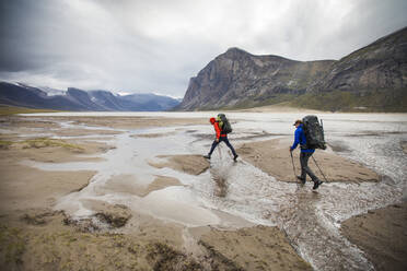 Two backpackers cross streams in Akshayak Pass, Baffin Island. - CAVF87358