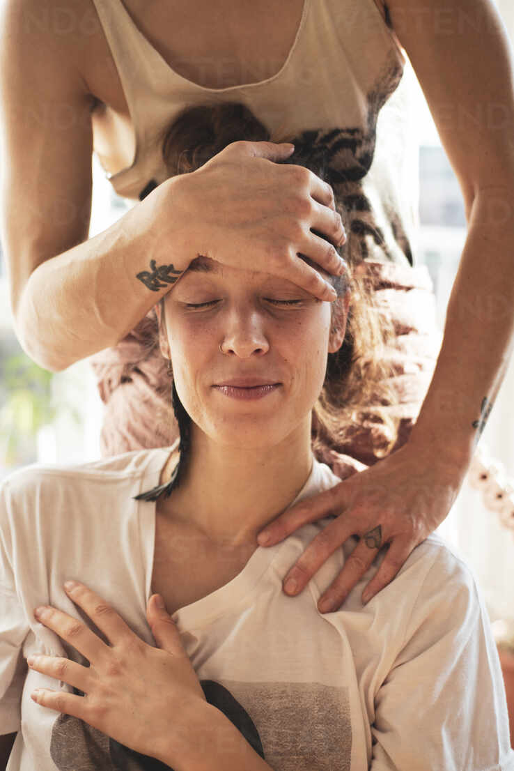 Home massage with same sex couple in warm light filled aparment stock photo