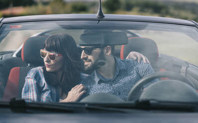Brunette woman in casual clothes and bearded man in shirt sitting in dark car and looking away - ADSF02182