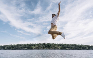 Man jumps joyfully by the lake. - ADSF02187