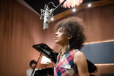 Lovely woman in casual outfit singing nice song white rehearsing with band in recording studio. - ADSF02202