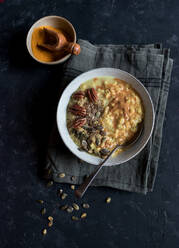 From above shot of bowl full of delicious oatmeal porridge with turmeric and grain standing on napkin on dark tabletop - ADSF02275